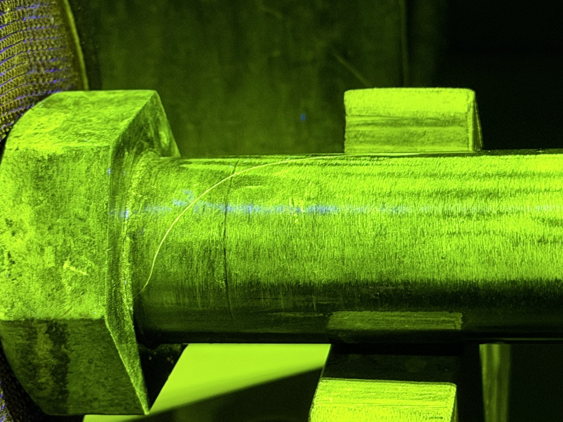 Fluorescent magnetic particle inspection revealing a crack in a bolt