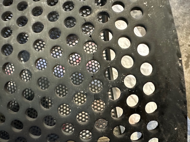 Visual inspection of a perforated component showing a crack across the surface